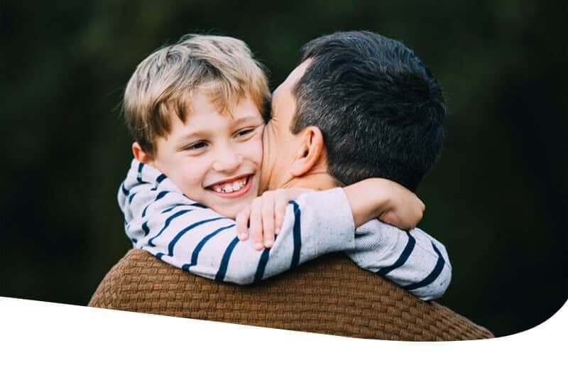 Smiling boy hugs dad tightly