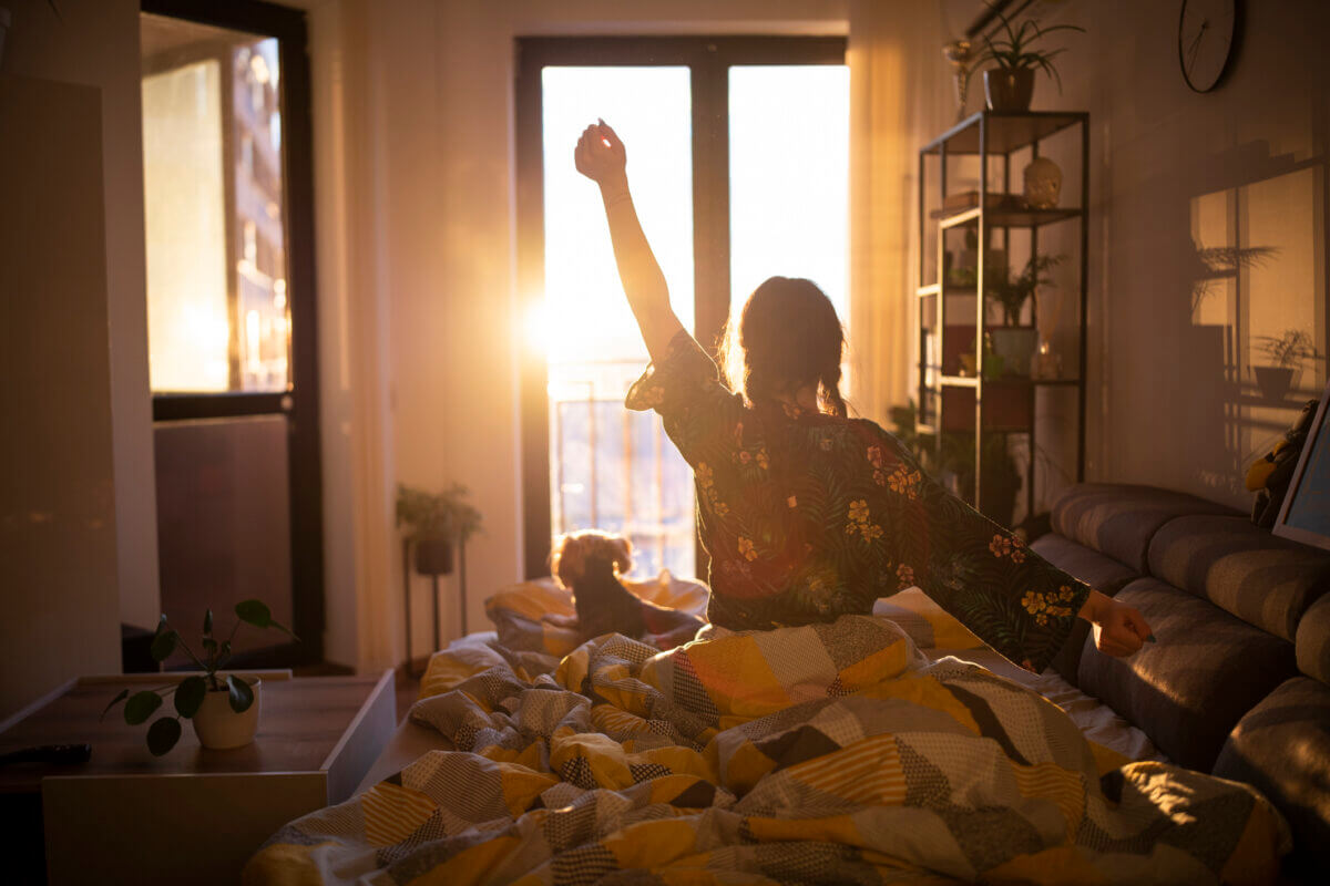 Woman wakes up to sunrise and stretches